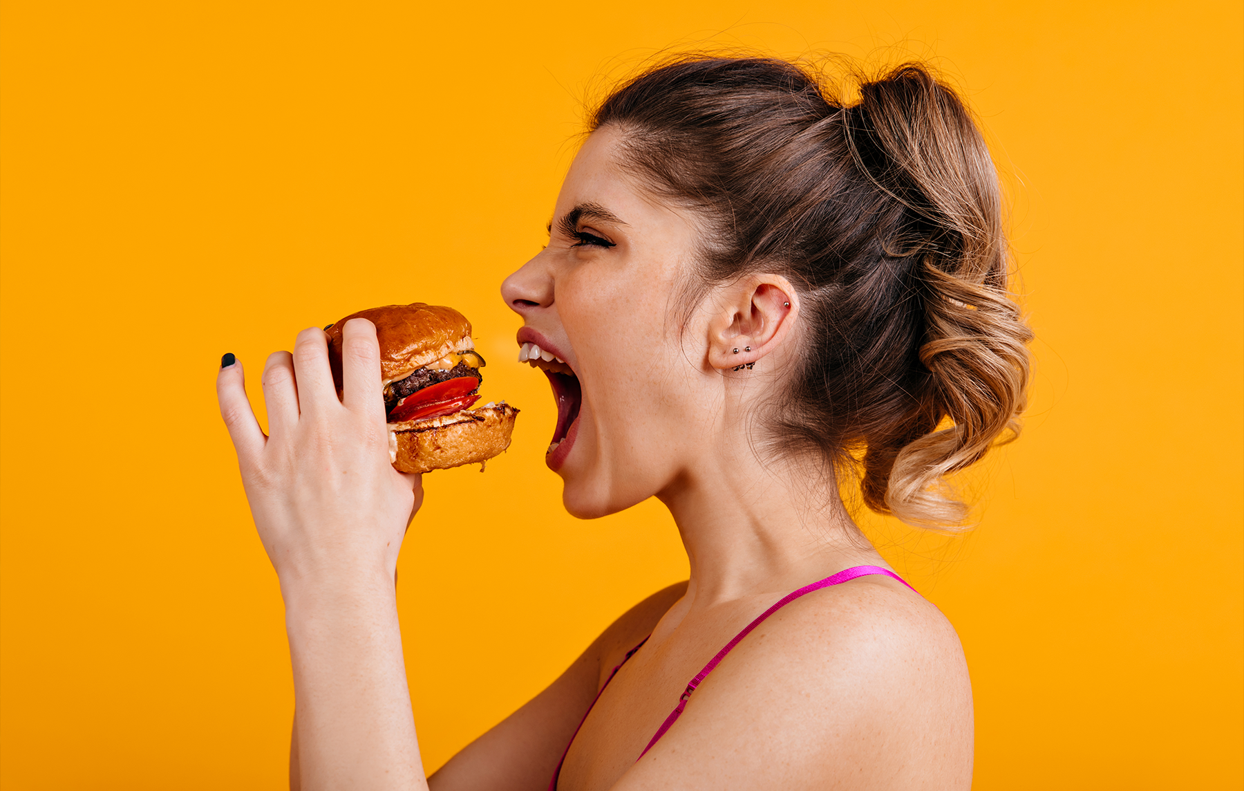 Kobieta jedząca burgera - w artykule staramy się odpowiedzieć, czy jedzenie ma wpływ na kondycję